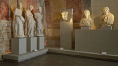 Blurry statues in a roman museum setting, featuring defocused busts and ancient stone sculptures creating a bokeh effect with visible historical details. clipart