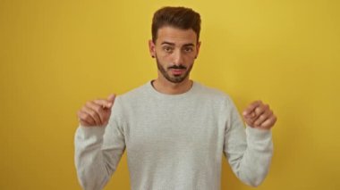 Canlı sarı bir arkaplan üzerinde hareketli İspanyol bir adam, kendine güvenen gri bir süveter giymiş karizma ve yüz ifadesini sergiliyor..