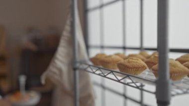 Kadın, telefonda konuşurken fırında maşayla kek kapıyor. Ticari mutfak ortamında birden fazla iş becerisi sergiliyor.