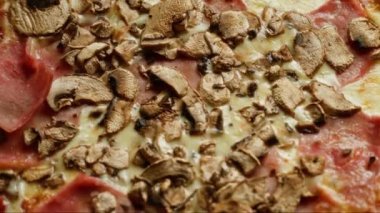 Mantarlı, jambonlu ve erimiş peynirli lezzetli bir pizzanın yakın çekimi, ağız sulandıran bir İtalyan yemeği tasvir ediliyor. Yemek sevenler ve aşçılar için mükemmel, reklam için ideal.