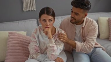 Bir erkek, sıcak, samimi bir oturma odasında, rahat bir evin içinde, bir kadını rahatlatıyor. İlişkiyi ve anlayışı ön plana çıkarıyor.