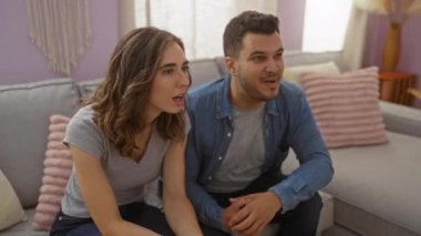 Mutlu çift evlerinin oturma odasında bir kanepede oturup el ele tutuşurken sevinçlerini ve heyecanlarını ifade ediyorlar.