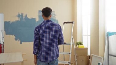 Oturma odasında duran genç adam, paketlenmemiş kutularla çevrili, parlak, geniş bir iç mekanda yeni başlangıçlar ve yeni gelişmeler hissi veriyor..