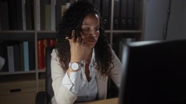 Geç saatlere kadar bir ofiste çalışan beyaz giyen bir kadın kalemle ciddi ciddi izliyor.