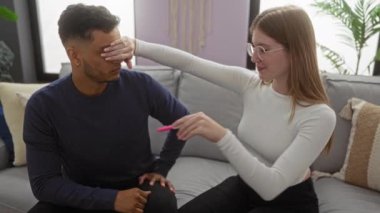 Sıcak ve samimi bir yuva ortamında neşeli ifadelerle sıcak oturma odasında pozitif hamilelik testini kutlayan çift.