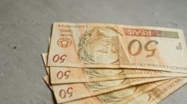 Brezilya banknotları 50 reais beton bir yüzey üzerinde düzenlenmiş, modern bir ayar ile Brezilya para birimi vurgulanıyor.