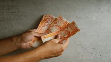 Filipinler 'de finans, para, ekonomi ve para işlemlerini temsil eden somut bir zemindeki Filipin pesolarını sayan eller