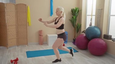 Spor salonunda yoga minderleri ve spor malzemeleriyle egzersiz yapan, sağlık ve etkinlik gösteren bir kadın..