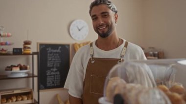 Pasta dükkanında sakallı, gülümseyen genç bir adam..