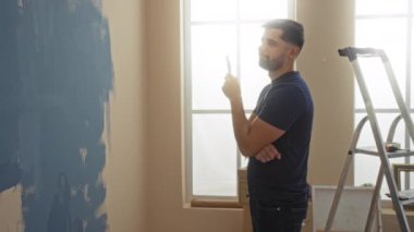 Modern apartman içinde resim yapmayı düşünen bir adam düşünceli bir ev yenileme sahnesi öneriyor..