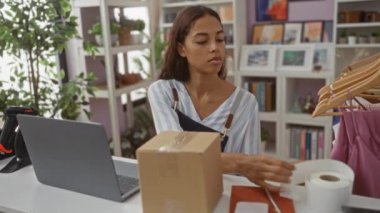 Ev dekorasyonu mağazasında dizüstü bilgisayarı ve çalışma alanı etrafında bitkileri olan bir kadın.