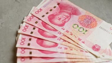 Çin Yuan banknotları somut bir yüzeye yerleştirilmiş, ayrıntılı tasarım elemanları ve renkleriyle 100 Yuan 'lık banknotları sergiliyorlar..