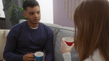 Kadın ve erkek kapalı bir koltukta oturuyor, sıcak bir oturma odasında kahvelerini yudumluyor, sıcak bir sohbet öneriyorlar..