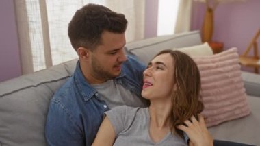 Kadın ve erkek evlerinde sevgi dolu bir anın tadını çıkarıyorlar, rahat bir oturma odasında, yumuşak doğal ışığı olan bir kanepeye yakın oturuyorlar..