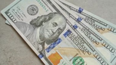 Amerika Birleşik Devletleri banknotları Benjamin Franklin 'in somut bir yüzeyde sergilenmesi, canlı detaylar ve mavi güvenlik şeridi ile yüz dolarlık banknotları vurguluyor..