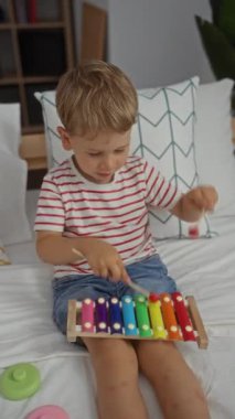 Parlak yatak odasında renkli ksilofonla oynayan çocuk, neşeli bir bebekle neşeli bir çocukluk anını gösteriyor evde müzik aktivitesi yapıyor..
