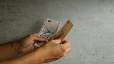 Elleri Türk lira banknotları ile beton bir arka plan üzerinde, farklı pozisyonlarda para birimlerini gösteriyor.