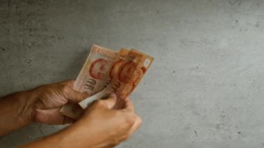 Elleri beton arkaplanda tek başına dolar sayan bir adam.