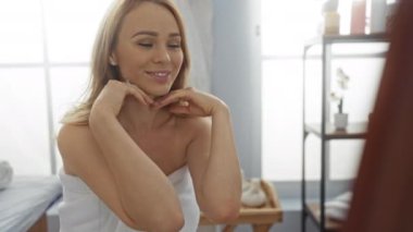 Huzurlu bir spa odasında gülümseyen, aynada yansıyan, sakin bir dekorla çevrili, rahatlamayı, sağlığı ve güzelliği vurgulayan bir kadın..