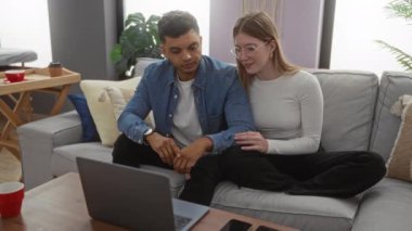 Oturma odasındaki kanepede oturan çift laptopta bir şeyler seyrediyor. Sıcak ve samimiyet saçıyor. Etrafı kapalı bitkilerle ve ahşap mobilyalarla çevrili..