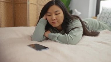 Sıcak bir yatak odasında uzanan kadın, aramasını bekliyor, beklentilerini dile getiriyor, sıcak, davetkar bir iç mekan ile çevrili, yumuşak tekstil ve nötr tonlarda..