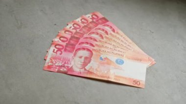 Filipinli pesolar, beton bir yüzeye serpiştirilmiş fan benzeri banknotlar halinde, para biriminin detaylı bir yakın çekimini sunar..