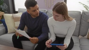 Evraklar ve tabletle rahat bir oturma odasındaki kanepede mali konuları tartışan bir çift..