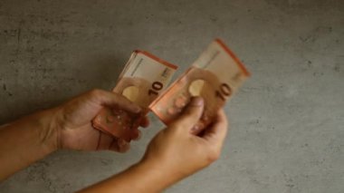 Somut bir geçmişi olan 10 avroluk banknotları sayan bir adam, mali işlemler veya bütçe planlaması öneriyor