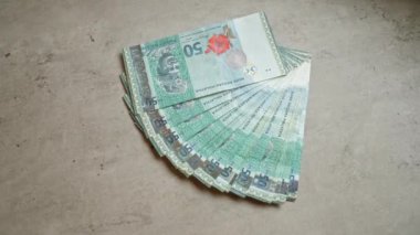 Malezya 50 ringgit banknotları beton bir yüzeye yayılarak, para biriminin karmaşık tasarımı ve canlı renklerini gözler önüne serdi.