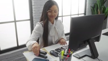 Ofiste çalışan bir kadın, yanında belgelerle masa başında çalışıyor. Gündüz vakti profesyonel bir çevreyi gözler önüne seriyor..