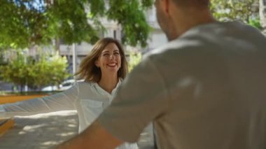 Kadın ve erkek, arka planda yeşillikle birlikte gündüz vakti şehir parkında mutlu mesut kucaklaşıyorlar.