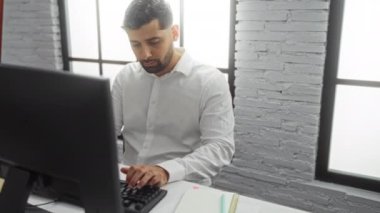 Modern bir ofiste çalışan genç bir adam, masasında bilgisayarla notlar alıyor, odaklanmış ve profesyonel bir atmosfer sergiliyor..