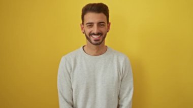 Gündelik süveter giyen genç adam neşeli bir ifadeyle canlı sarı arka plana öpücük yolluyor..