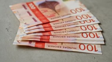 Somut bir yüzeyde sergilenen 100 kronluk Norveç banknotları para birimi tasarımı ve finans temasını gözler önüne seriyor.