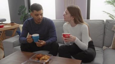 Samimi oturma odasında kahve içip eğlenen çift içeride dostluk ve rahatlama ima ediyor..