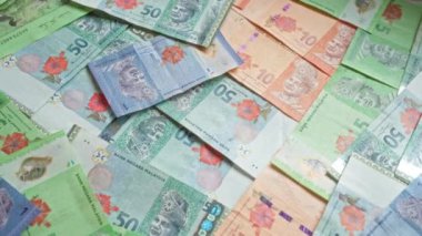 Malezya banknotları 1, 5, 10 ve 50 ringgit dahil olmak üzere çeşitli banknotlar Malezya 'nın para birimini gösteren bir yüzey üzerine dağılmıştır..