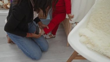 Diz çökmüş bir kadın, kırmızı elbiseli bir çocuğa oyuncak dolu rahat bir yatak odasında ayakkabılar ve aile ortamını geliştiren beyaz bir sandalye verir..