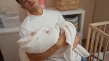 Beyaz bir battaniyeye sarılmış, sıcak bir hastane odasında uyuyan, yeni babalığı ve baba ile çocuk arasında paylaşılan şefkatli ve barışçıl bağı temsil eden İspanyol genç bir adam..