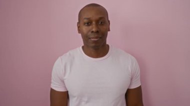 İzole edilmiş pembe arka planda gülümseyen genç bir adam neşeli ve kendinden emin bir ifade çiziyor. Olumlu duygular, dostça ve davetkar tavırları yansıtıyor.