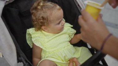 Bebek arabasında beslenen bir kadınla abur cubur yiyen bir çocuk.