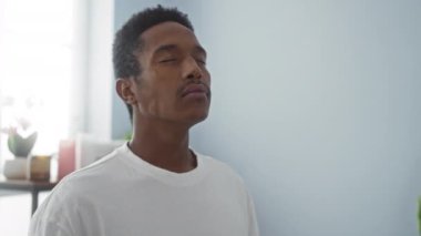 Genç bir adam gözlerini kapamış, kaplıcaya bakıyor, beyaz gömlek giyiyor, minimalist bir sağlık merkezinde sükunet ve rahatlık sergiliyor..