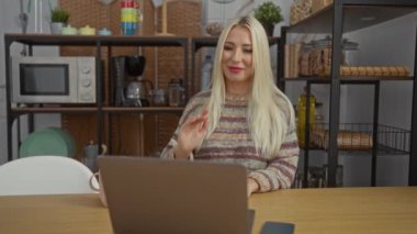 Samimi bir mutfakta dizüstü bilgisayarla gülümseyen ve mutlu görünen bir kadın..