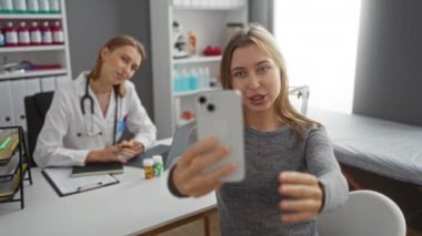 Klinikte gülümseyen doktorla selfie çeken bir kadın sağlık hizmetleri seti ve tıbbi iş yerindeki dost canlısı hasta deneyimlerini vurgulayan teknoloji etkileşimi sergiliyor..