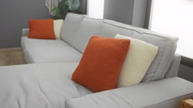 Rahat bir kanepede, rahat bir oturma odasında, canlı yastıklarla dinlenen bir kadın..