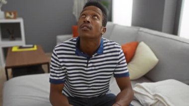 Evdeki genç adam, üst kattaki gürültüden bıkmış oturma odasında oturmuş, kulaklarını tutmuş, yukarıyı seyrediyor, rahat ve şık bir yuva kurmaya çalışıyor.