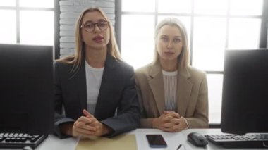 Modern ofiste masa başında oturan kadın yöneticiler, iş toplantılarına katılıyorlar, takım çalışması ve profesyonel giysiler sergiliyorlar, masada bilgisayarlar ve pencerelerden güneş ışığı akıyor..