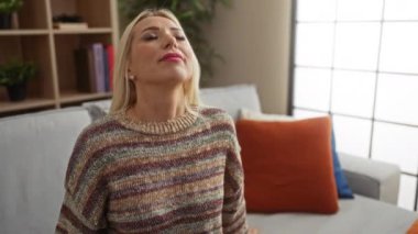 Şık bir oturma odasında rahat bir kanepede dinlenen bir kadın, sıcak, iyi dekore edilmiş bir ev ortamında huzur ve sükunet yayıyor..