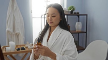 Cilt bakımı odasında beyaz bornoz giyen Asyalı bir kadın. Huzurlu bir ortam yaratıyor..