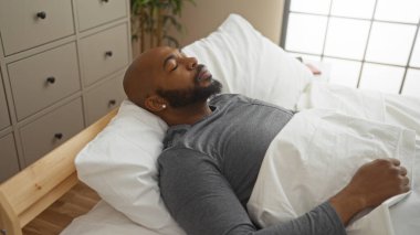 Yakışıklı genç adam, rahat bir yatak odasında, yumuşak bir yastıkla huzur içinde uyuyor.