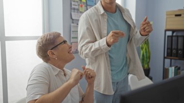 Kadın ve erkek neşeli bir ofis ortamında çalışmaktan zevk alıyor, çalışanların olumlu etkileşimlerini ve kapalı alanda takım çalışmalarını sergiliyor..